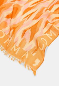 Pomarańczowy szalik z różowym i jaśniejszym pomarańczowym abstrakcyjnym wzorem, z frędzlami na brzegach i subtelnym logo w jaśniejszym odcieniu.