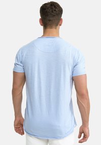 Lyseblå kortærmet t-shirt i et blødt, tekstureret stof, med en rund halsudskæring og en afslappet pasform med en længere bagkant.