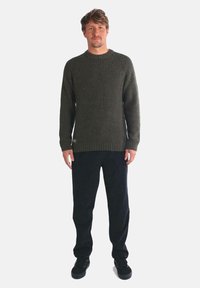 Suéter de canalé verde oliva con mangas largas, escote redondo y tejido texturizado. Combinado con pantalones oscuros y zapatillas negras.