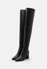 Black leather over-the-knee boots with pointed toes, block heels, and seam detailing along the top. Smooth texture with a sleek design.