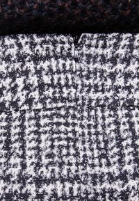 Textile à motif pied-de-poule noir et blanc, avec fermeture éclair ; tissu texturé au toucher tissé.