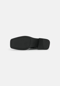 Suela de zapato negra con una superficie suave y texturizada, de forma redondeada y patrones de piso sutiles para mayor agarre. Sin marcas visibles.