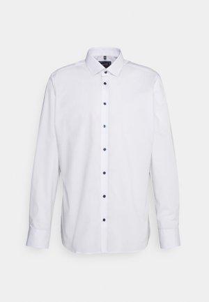 Biała męska koszula wizytowa z długim rękawem, kołnierzem typu spread oraz ciemnymi guzikami, na jednolitym jasnoszarym tle.