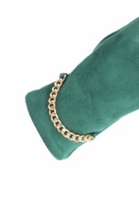 Borsa in suede verde con tracolla in catena dorata. Texture liscia con silhouette arrotondata e senza pattern visibili o hardware aggiuntivo.