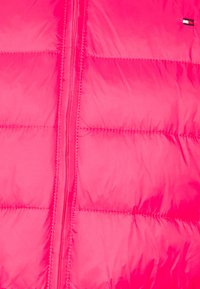 Padded pink jacket mit Reißverschluss, mit gesteppten Abschnitten und einem kleinen Logotag oben rechts. Glatte, glänzende Textur.