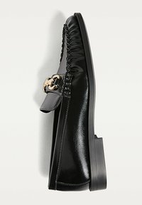 Černé kožené mokasíny s mírným podpatkem, s tkaným designem na svršku a zlatým páskem jako akcentem na boku.