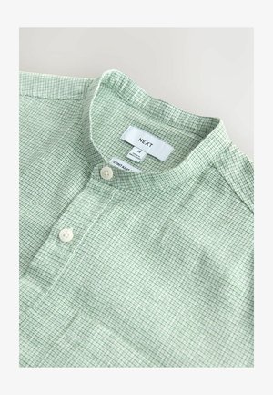 Zielona koszula w wzory z kołnierzykiem typu mandarynka, wykonana z teksturowanej tkaniny, z dwoma białymi guzikami i metką z informacjami o marce.