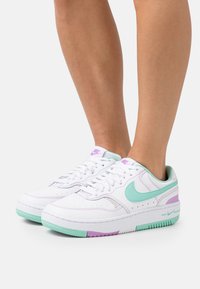 White leather sneakers featuring mint green and lavender accents, perforated detailing, and a textured sole. Low-top design.