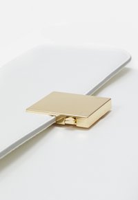 Bílá kožená psaníčko s lesklým zlatým čtvercovým zapínáním, vyznačující se čistými liniemi a hladkým povrchem. Minimalistický design zdůrazňuje moderní eleganci.