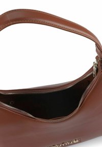 Braune Lederhandtasche mit glatter Textur, Reißverschluss und einem einzelnen Schulterriemen. Das Innere ist schwarz und zeigt ein minimalistisches Design.