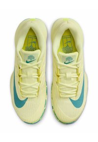 Zapatos deportivos de color amarillo claro con una parte superior texturizada, logotipo de swoosh azul y patrón de suela verde. Incluyen cordones y un collar acolchado.