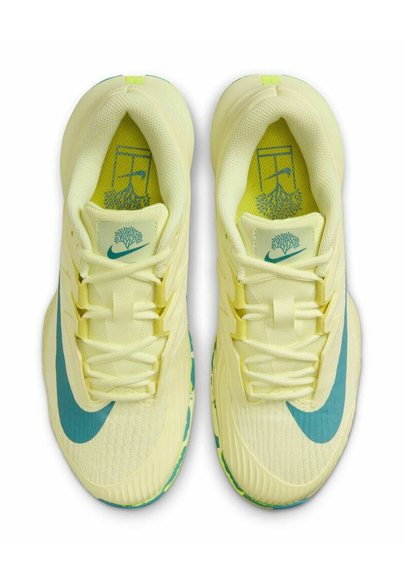 Scarpe da ginnastica giallo chiaro con tomaia testurizzata, logo swoosh blu e motivo della suola verde. Le caratteristiche includono lacci e colletto imbottito.