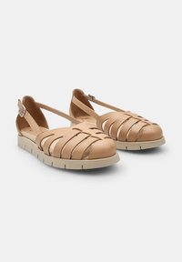 Sandalias de cuero marrón con un diseño de tiras y recortes, punta redonda y una suela de goma de color claro para mayor comodidad y soporte.