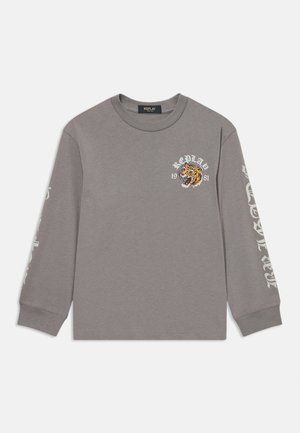 Hallitatud hall pikkade varrukatega T-särk, mis on valmistatud puuvillast, sisaldab tigrimeelse graafikat ja brändimist rinnaosas ning teksti aktsente varrukatel.