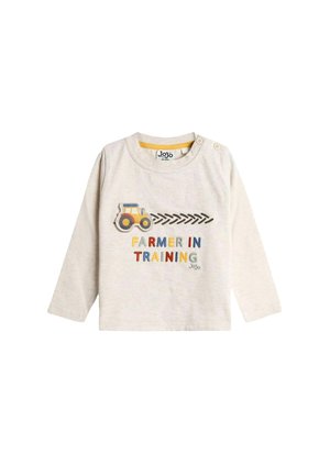 Langärmliges, hellbeiges Baumwollhemd mit dem Text "Farmer in Training" in bunten Buchstaben und einer gelben Traktor-Grafik auf der Vorderseite.