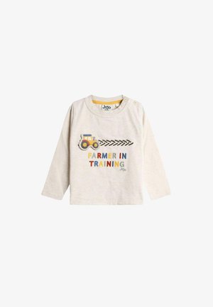 Dlhý rukáv, svetlo béžová bavlnená košeľa s textom "Farmer in Training" v farebných písmenách a žltou grafikou traktora na prednej strane.