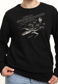 Black sweatshirt featuring a gray illustration of an X-wing and TIE fighters from Star Wars, with the logo above in a stylized font.