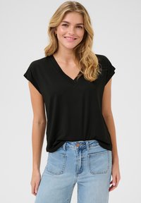 Czarny t-shirt w serek w luźnym kroju z krótkimi rękawami, zestawiony z jasnoniebieskimi spodniami z wysokim stanem. Miękki materiał, brak widocznych wzorów lub akcentów.