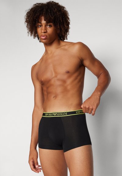 Boxer aderenti neri con una fascia gialla Emporio Armani, realizzati in tessuto morbido con design aderente e cuciture minime.