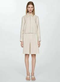 Beige cropped jacka med dragkedja fram, i kombination med matchande skräddarsydda shorts. Slät textur, minimalistisk design och korta ärmar.