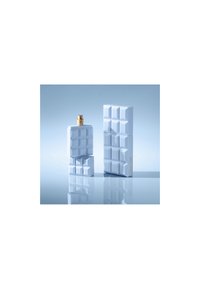 Hvit parfymeflaske sett med teksturert, geometrisk design. Den ene flasken er høyere med en gull spraydyse; begge har en blank finish.