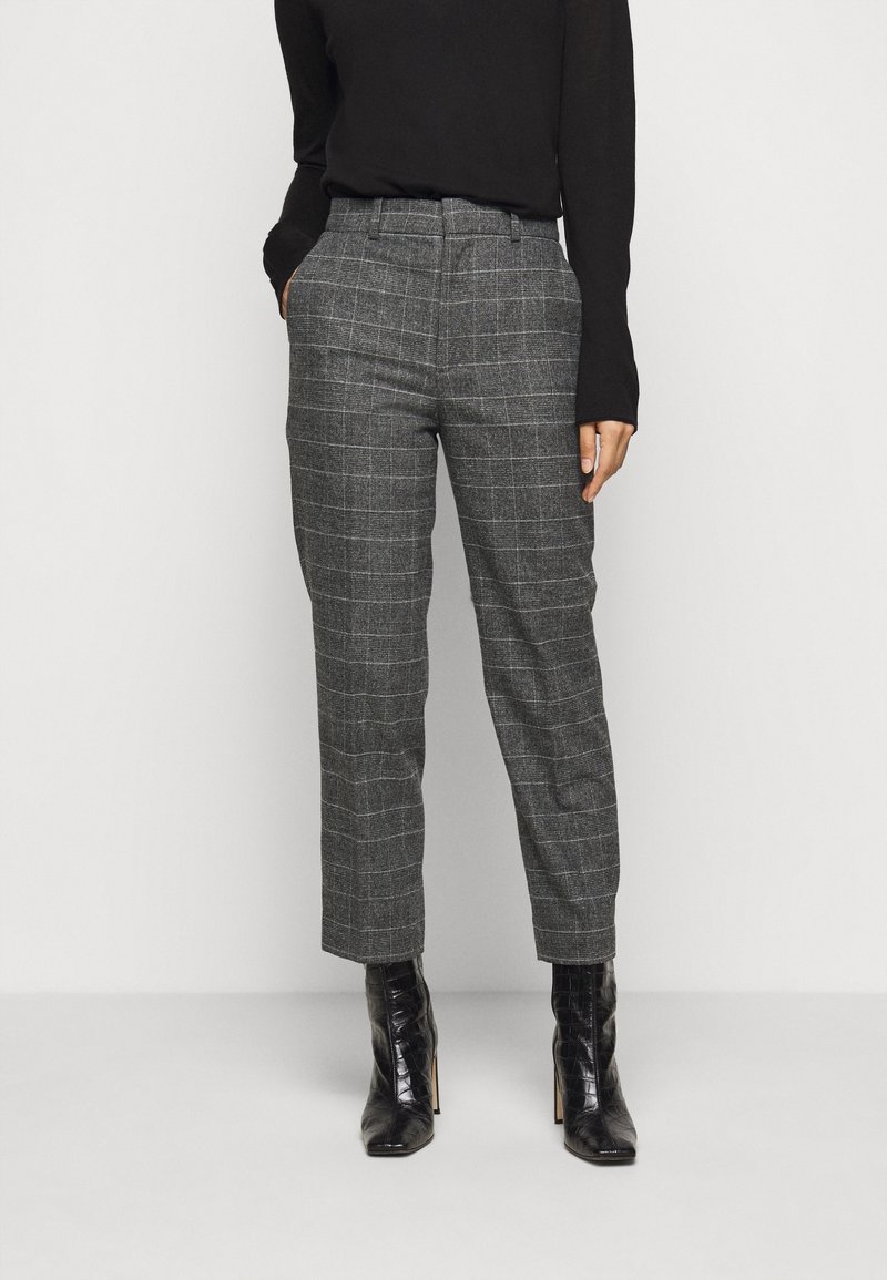 Pantalons à carreaux gris avec une coupe ajustée, présentant une taille haute, des poches et un pli sur le devant ; assortis à des bottes à talons hauts noires.