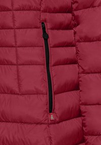 Rode pufferjack met een gepluceerde textuur, voorzien van een zwarte rits en een klein logo-label nabij de rits. Glad materiaal met een glanzende afwerking.