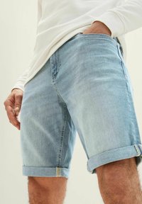 Pantalones cortos de mezclilla azul claro con dobladillos enrollados, que presentan un diseño clásico de cinco bolsillos y un ligero desgaste en la tela.