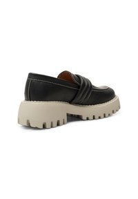 Crne kožne loaferice s ukrasnim križnim detaljima, koje imaju debeli bež gumeni potplat s dubokim utorima za prianjanje.