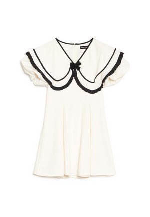 Vestido crema con cuello grande con borde negro, bordes de volantes negros, mangas cortas abullonadas y un pequeño lazo negro en el escote.