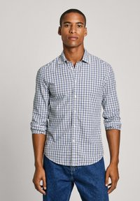 Camisa de botones con patrón de cuadros azules y blancos, de mangas largas arremangadas hasta los codos y un bolsillo en el lado izquierdo.