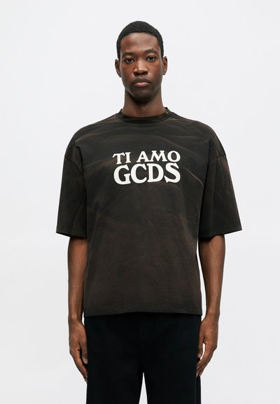 Svart oversized t-skjorte laget av bomull, med rund hals og fronttekst i hvitt: "TI AMO GCDS." Korte ermer og en avslappet passform.