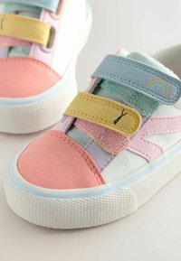 Kolorowe sneakersy z teksturowaną białą podeszwą, z różowym zamszowym czubkiem, wielokolorowymi rzepami oraz dekoracyjnymi akcentami w postaci motylków i tęczy.