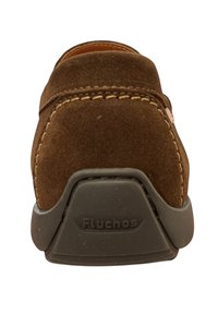Scarpa in suede marrone con punta arrotondata, cuciture a contrasto in tan, suola in gomma e "Fluchos" impresso sul tallone. Texture morbida, design semplice.