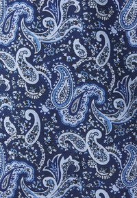 Blå och vit paisleymönster med blommor och vinrankor på en mörkblå tygbakgrund.