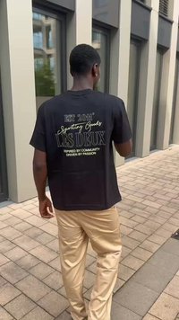 Camiseta negra de manga corta con texto dorado en la parte de atrás, que presenta "EST 2011 Sporting Goods LES DEUX" y detalles adicionales.