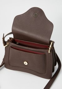Sac à main en cuir marron avec une surface texturée, des accents en matériel doré, un intérieur bordeaux et une fermeture à rabat. Sangle réglable incluse.