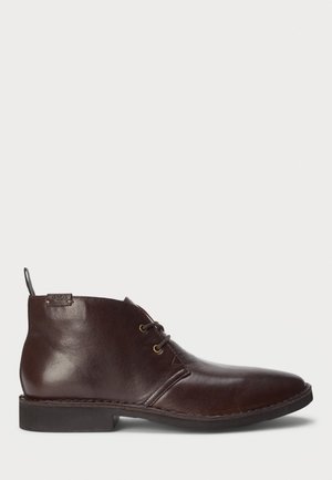 Bottine en cuir marron foncé avec laçage à l'avant, petit talon et languette de tirage marquée à l'arrière.