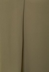 Gros plan sur un tissu vert olive lisse avec un pli vertical au centre.