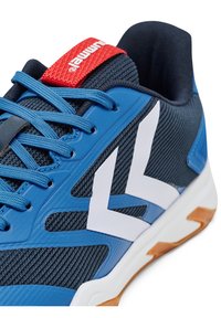Niebieski but sportowy z teksturowaną siateczkową cholewką, białymi akcentami, czerwoną metką na języku i gumową podeszwą, podkreślający sportowy styl i sznurowanie.