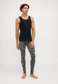 Black tank top paired with green camo leggings. The leggings feature a textured pattern in dark and light green shades.
