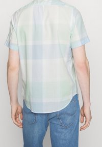 Kurzärmliges kariertes Hemd in hellblauen und grünen Farbtönen mit abgerundetem Saum. Leichter Stoff und dezente Textur, mit Schulterpasse hinten.