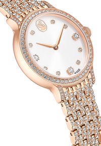 Roségouden horloge met een ronde wijzerplaat, witte wijzerplaat en kristallen versieringen. Voorzien van een mesh band met meerdere kleine edelstenen in het ontwerp verwerkt.