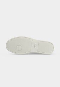Semelle d'une chaussure blanche avec une accroche texturée, un motif circulaire près des orteils et le logo "BOSS" embossé dans la zone de la semelle intermédiaire.
