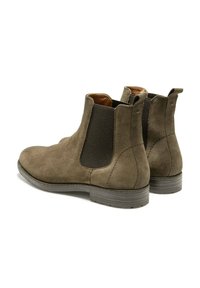 Des bottes Chelsea en suede olive foncé avec des panneaux latéraux en élasthanne, un bout arrondi et un petit talon empilé, ornées de détails de couture subtils et d'une doublure intérieure.