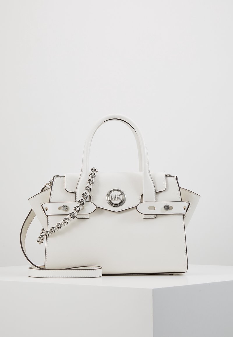 Sac à main en cuir blanc avec double poignée, détail chaîne argentée, fermeture à rabat et un logo rond MK argenté sur le devant, exposé sur une surface blanche.