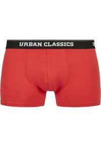 Boxer rouge en coton avec une taille noire portant le texte "URBAN CLASSICS" en blanc. Texture lisse et design ajusté.