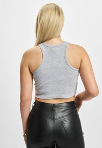 Hallhalline ribadega lühike tank top, ümarate kaelustega, koos mustade vale nahast kõrge talje pingutustega pükstega, millel on taga taskud ja õmblustooted.