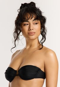 Čierny bandeau bikiny top s riasením, hladkou textúrou a bez viditeľného hardvéru. Navrhnutý bez ramienok pre čistý silueta.