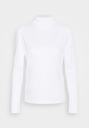 Witte, lange mouw, coltrui met een getailleerd silhouet op een effen lichtgrijze achtergrond.